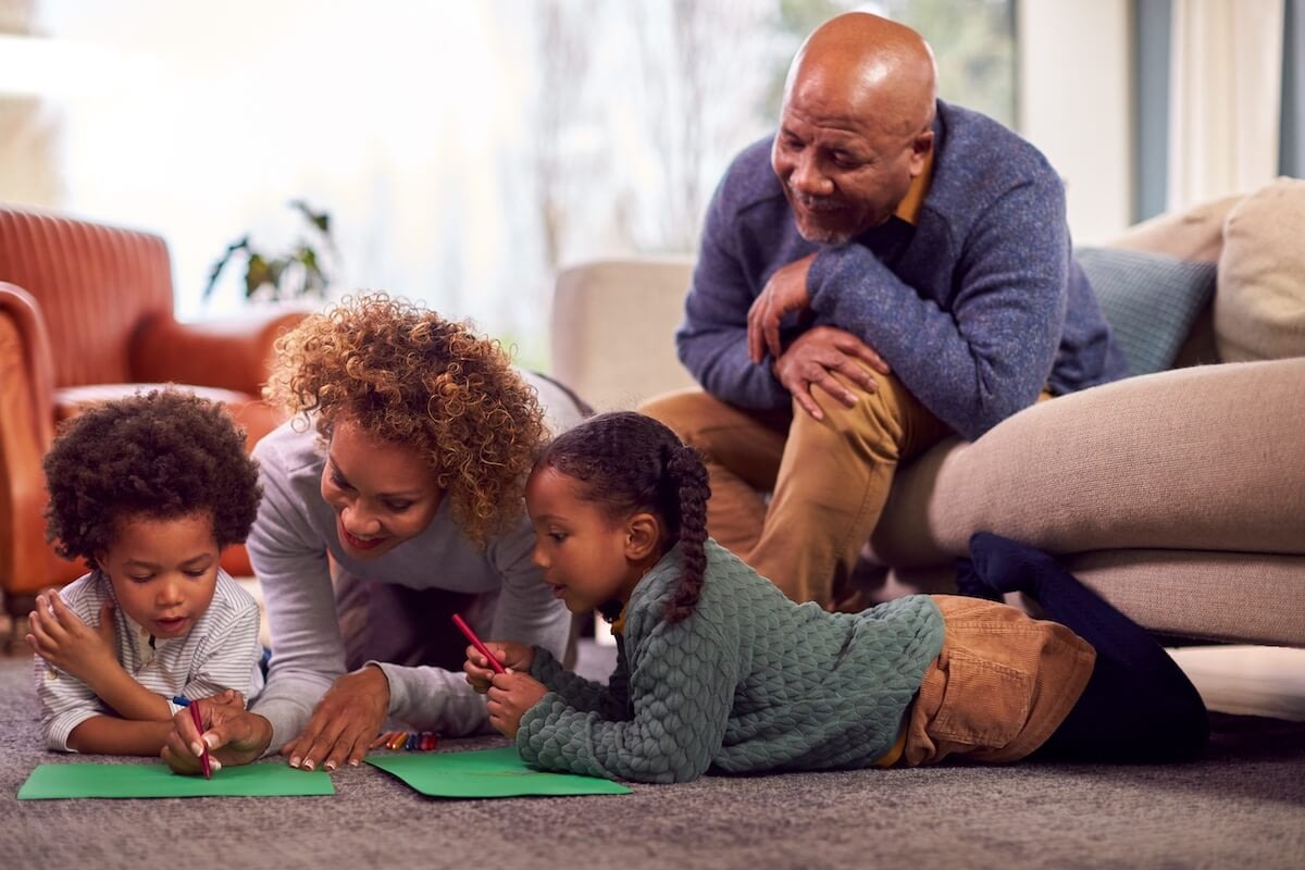 Family drawing together on living room floor