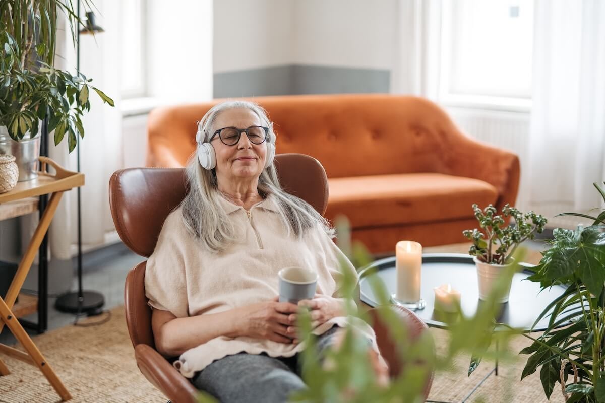 Senior woman relaxing with headphones and coffee
