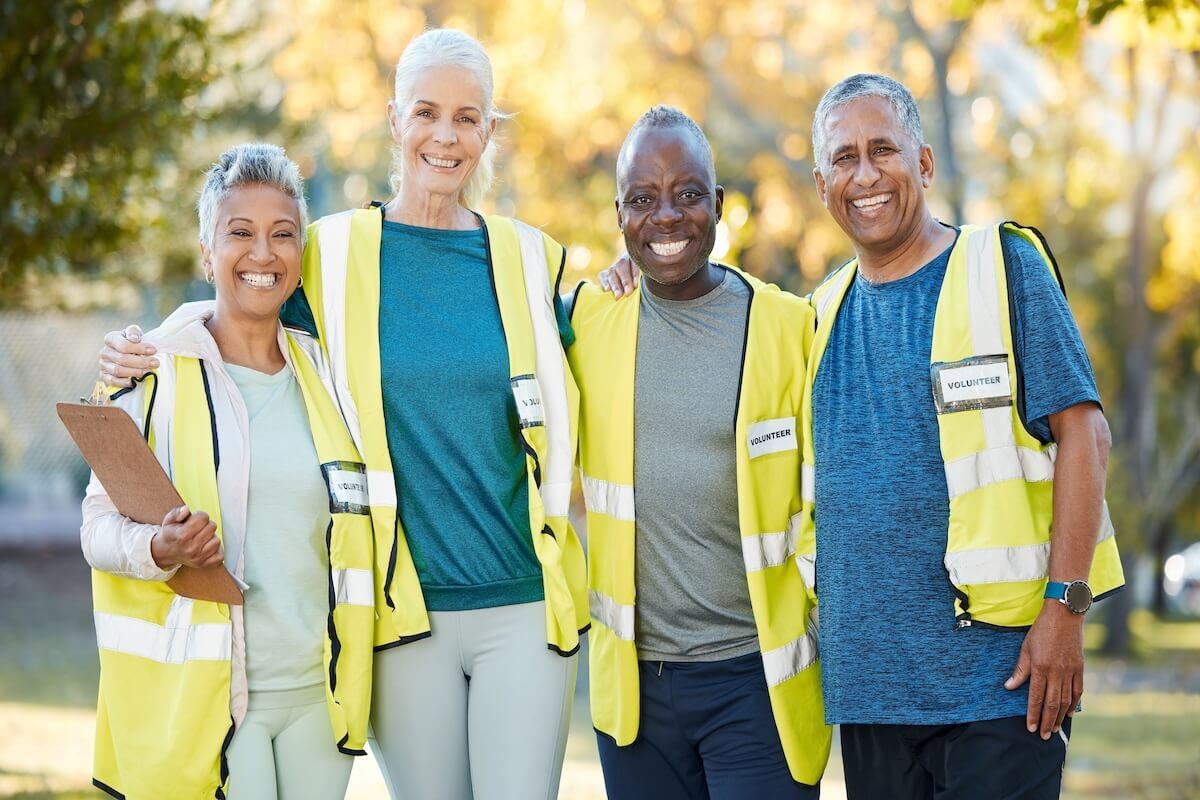 Four senior volunteers wearing safety vests outdoors