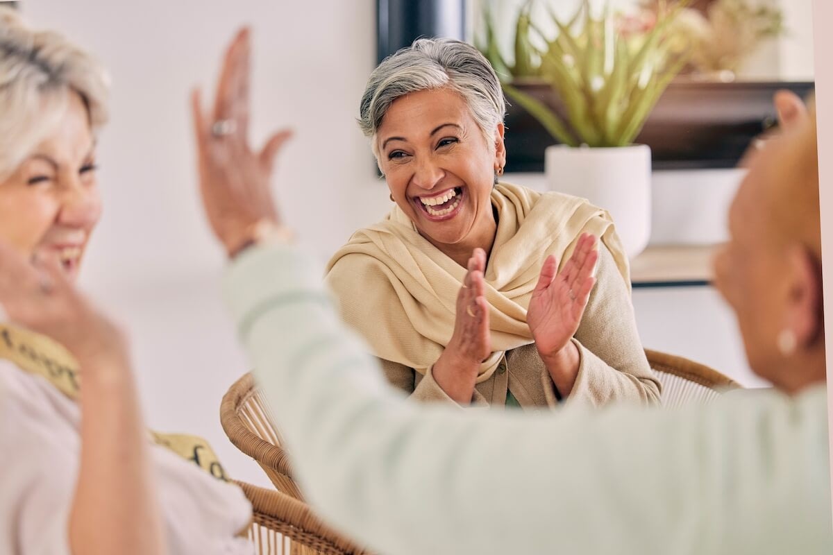 Three women laughing and high-fiving indoors