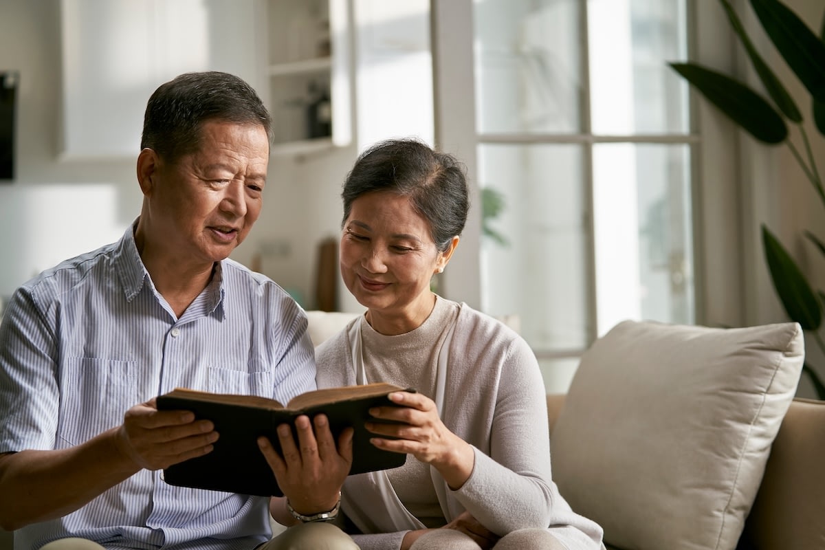 Older couple reading book together on couch