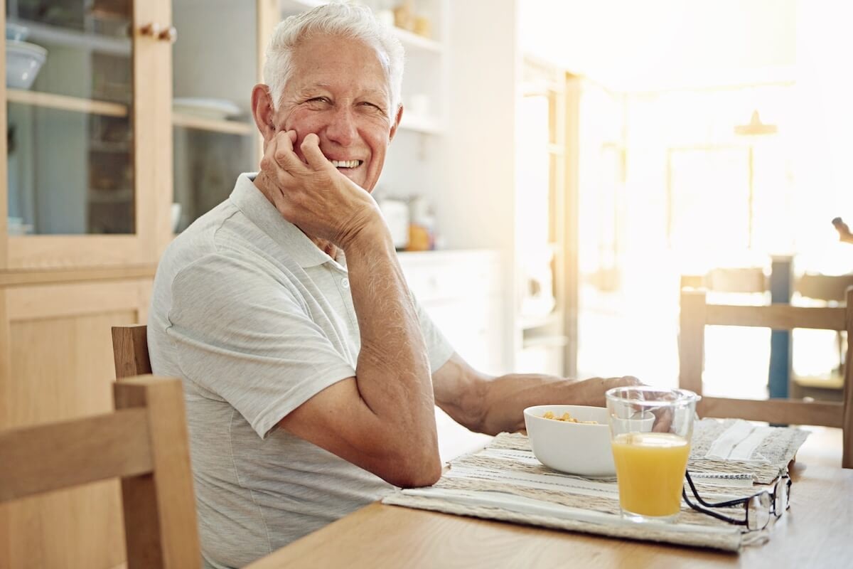 Smiling senior man eating breakfast at table
