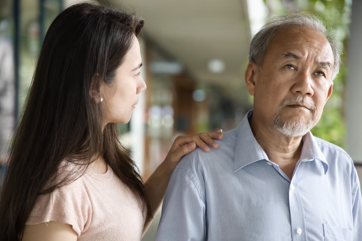 Woman comforting older man indoors