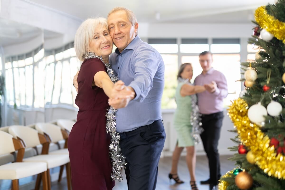 Senior couples dancing near decorated Christmas tree