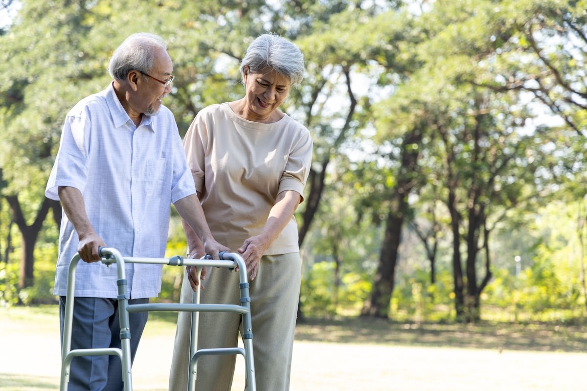 Elderly couple walking with walker in park