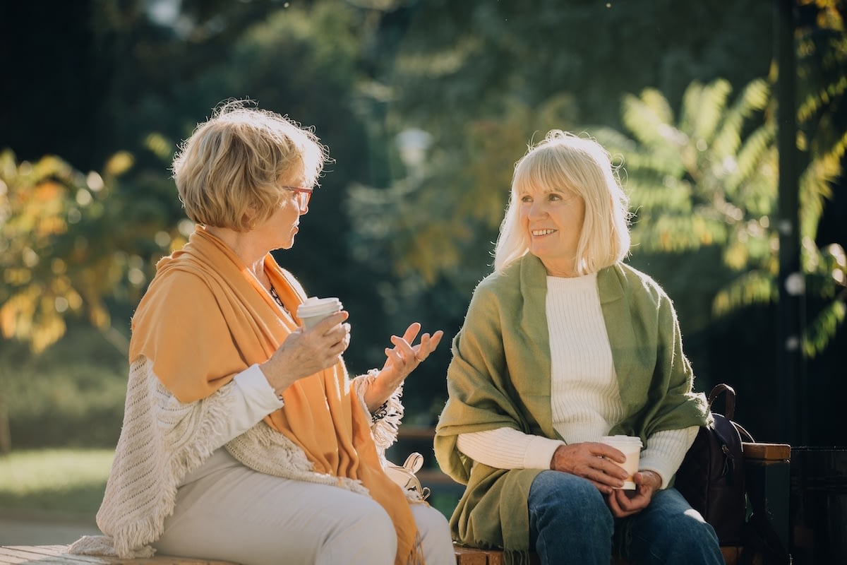 Two older women chatting on park bench