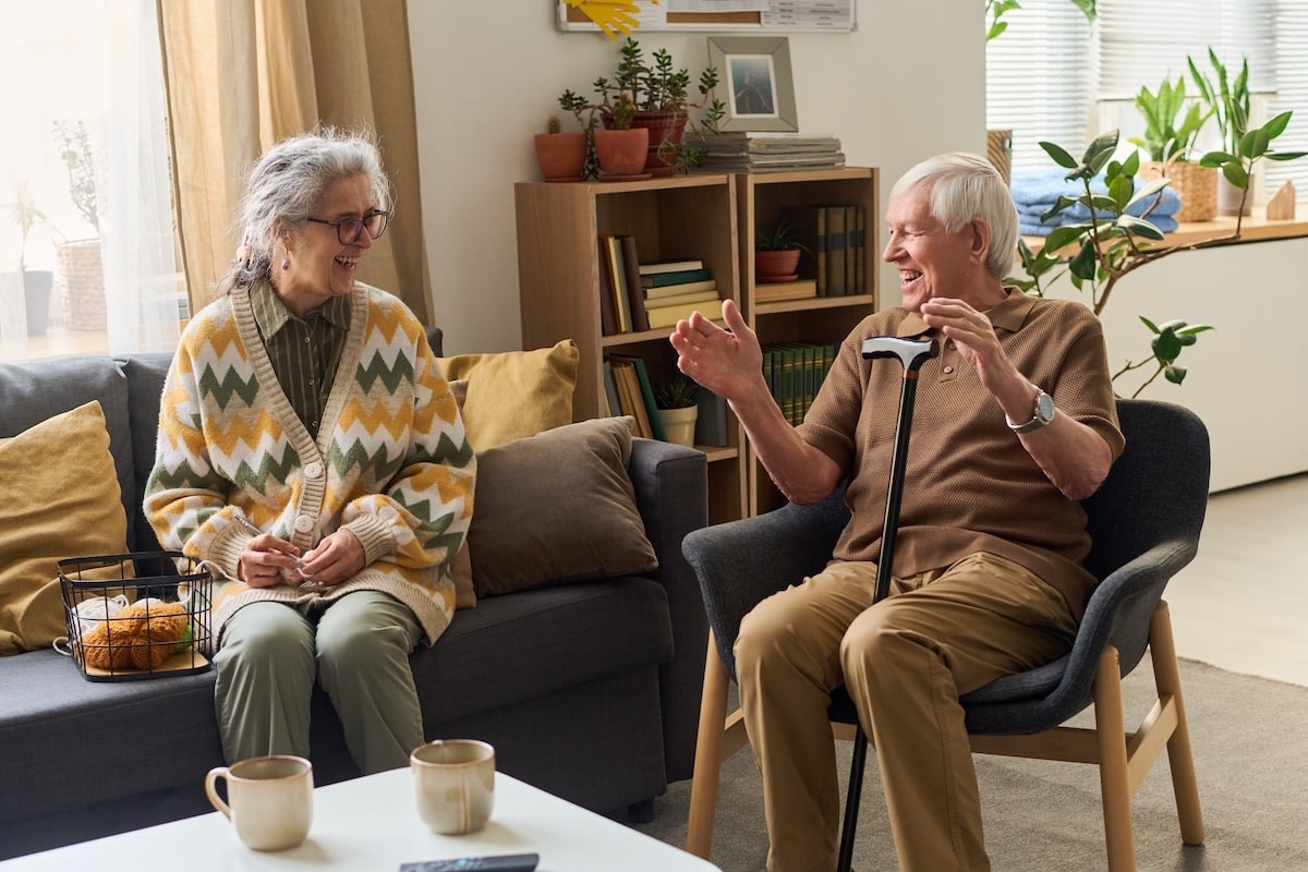 Elderly couple laughing together in cozy living room