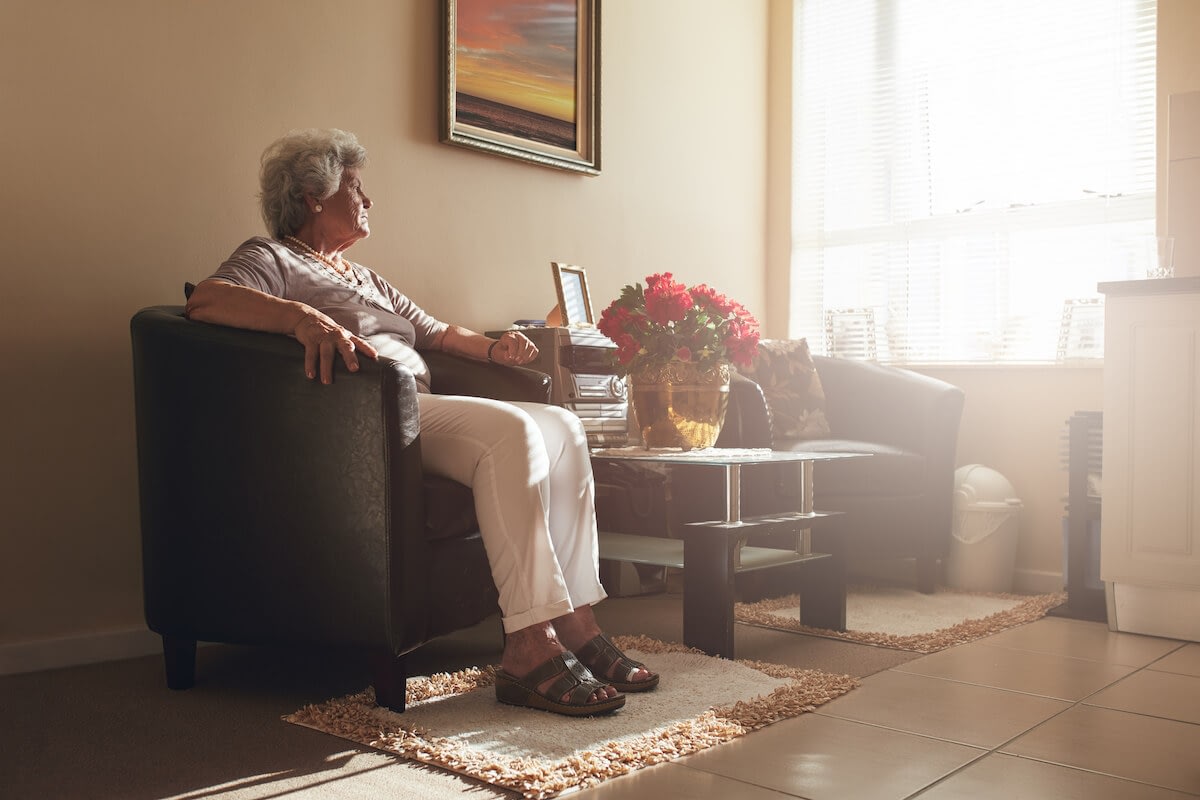 Elderly woman sitting in sunlit living room
