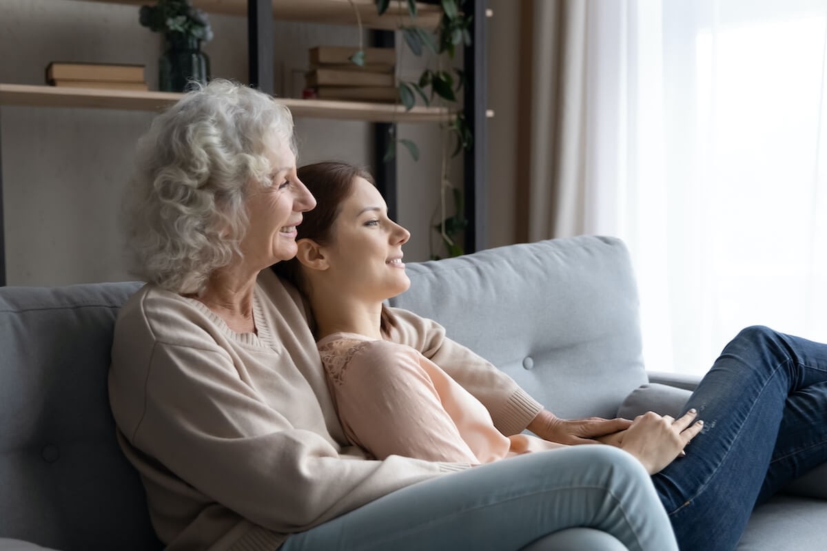 Grandmother and granddaughter smiling on living room couch