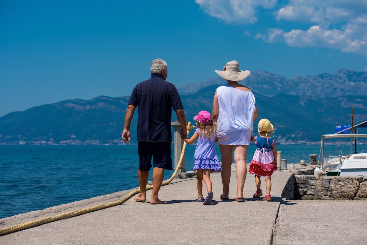 Family walking on seaside pier with mountains
