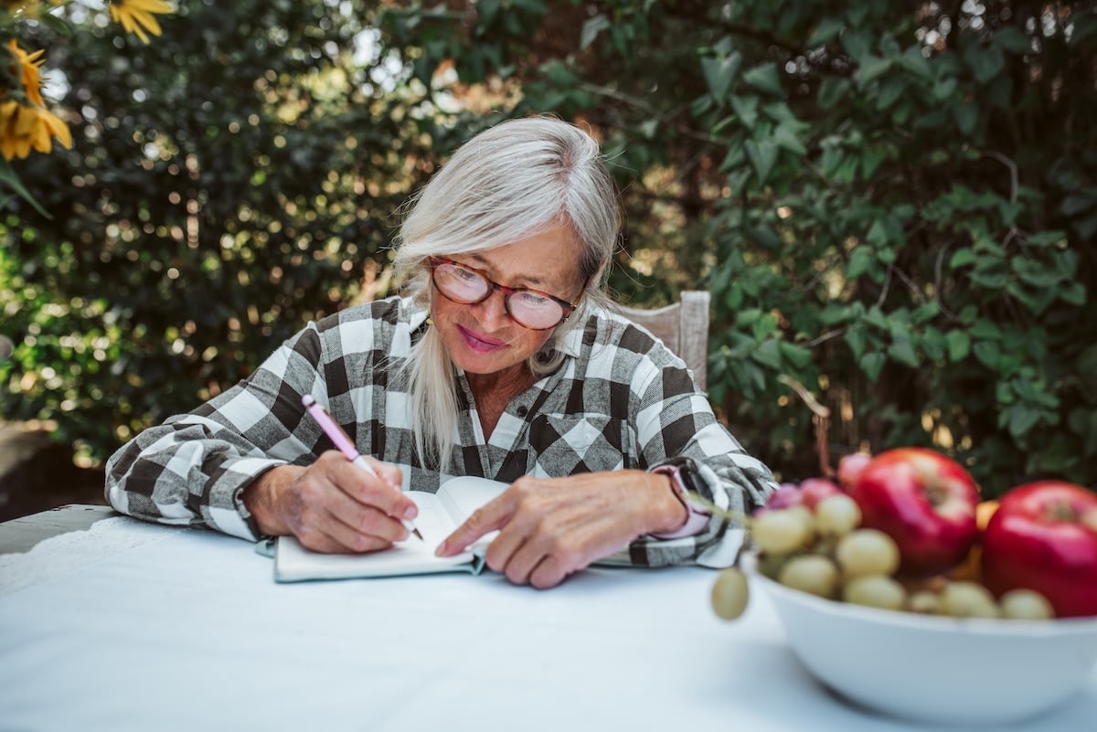 Older woman writing in notebook outdoors