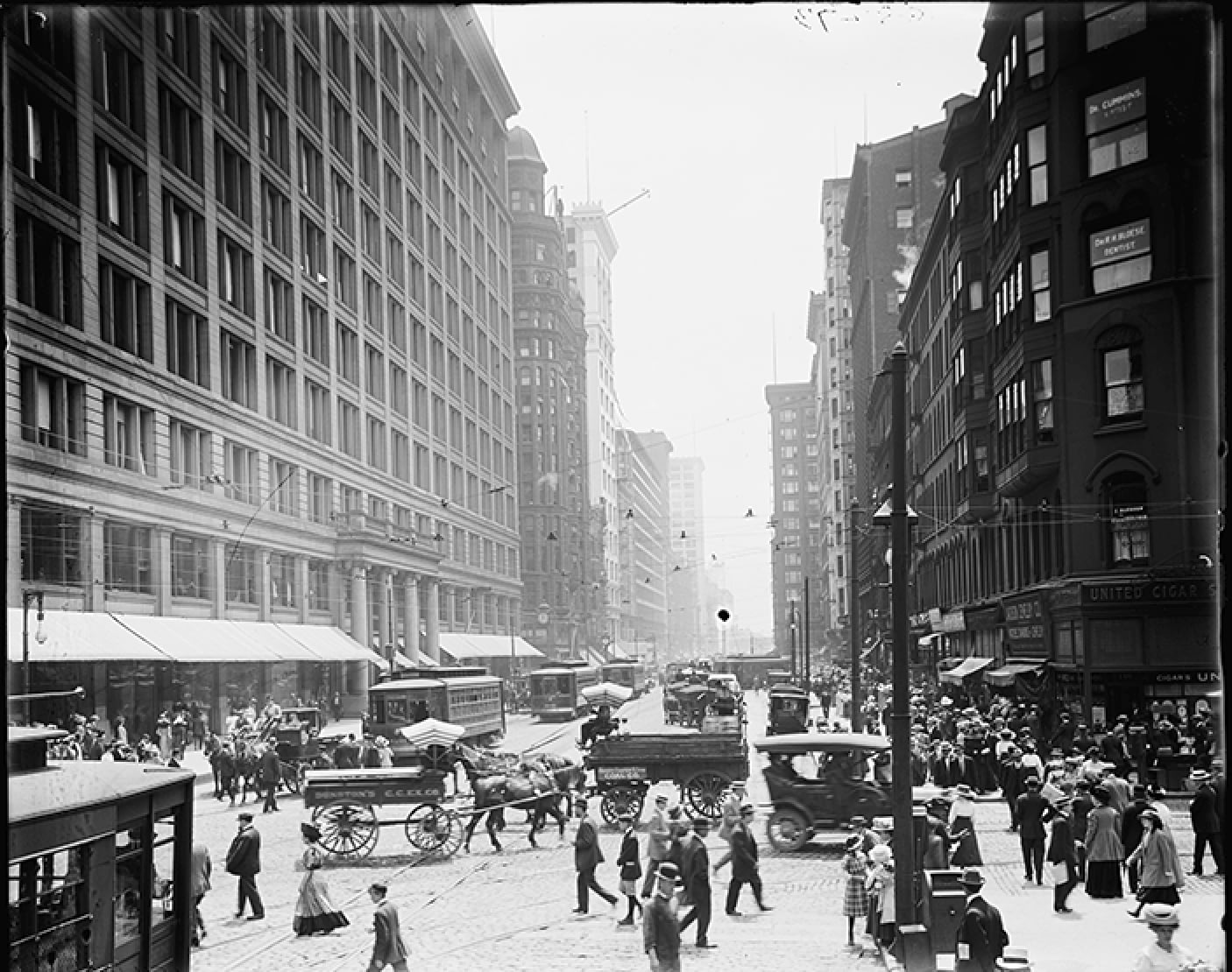 Busy early 1900s city street with carriages