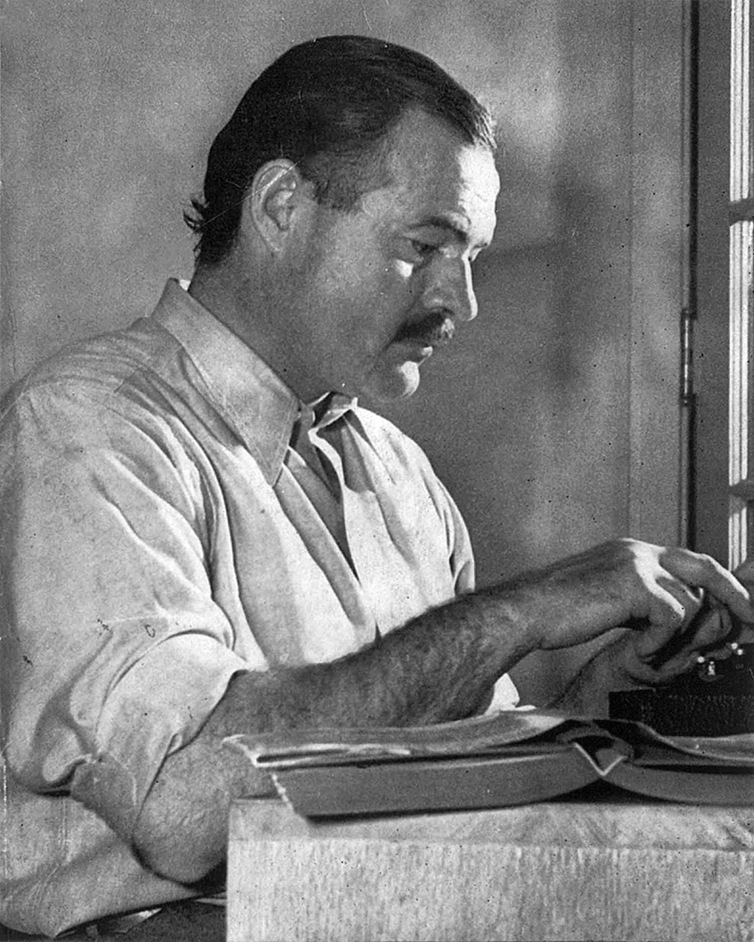 Man typing on typewriter by window