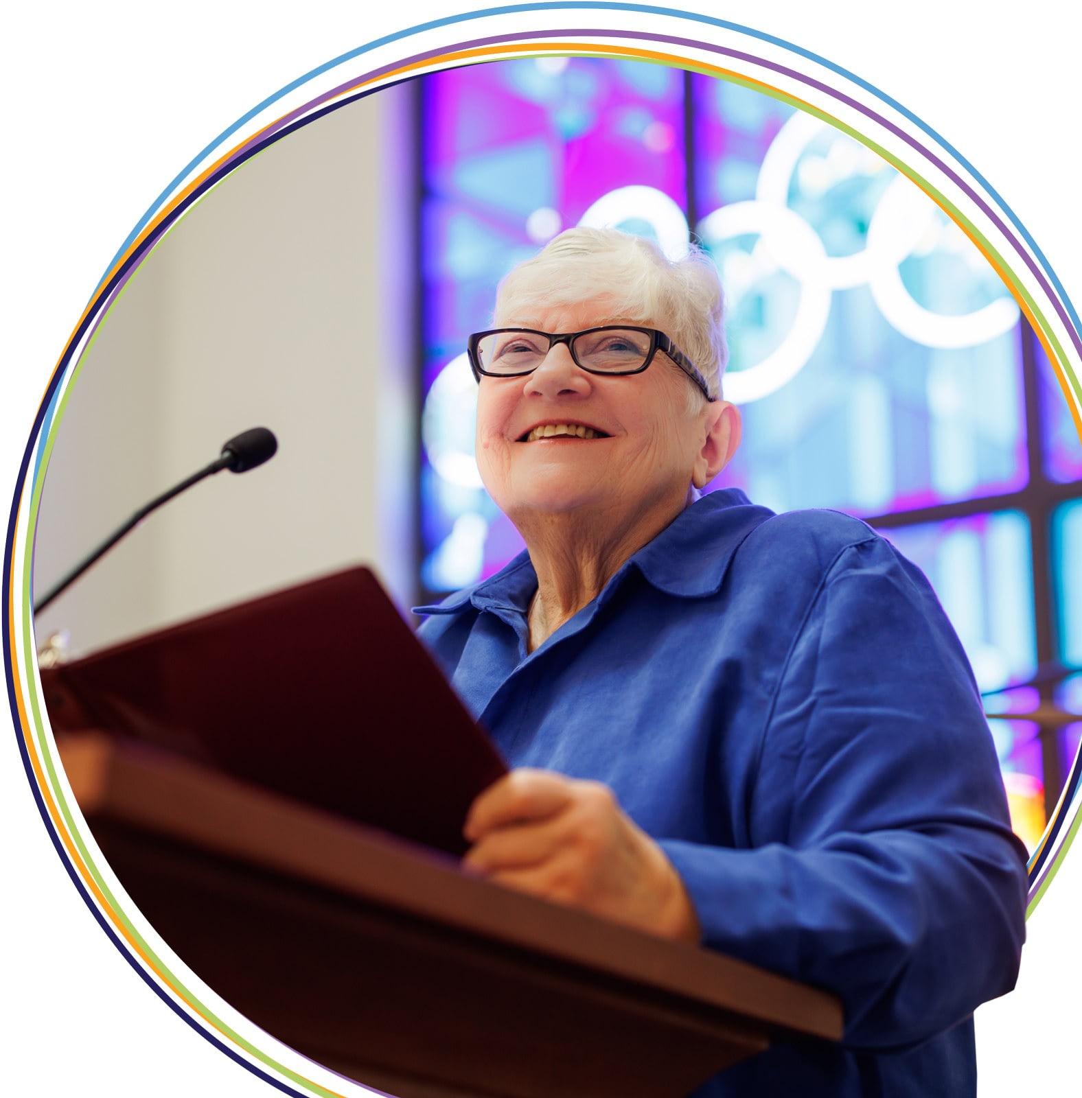 Elderly woman speaking at podium with Olympic rings