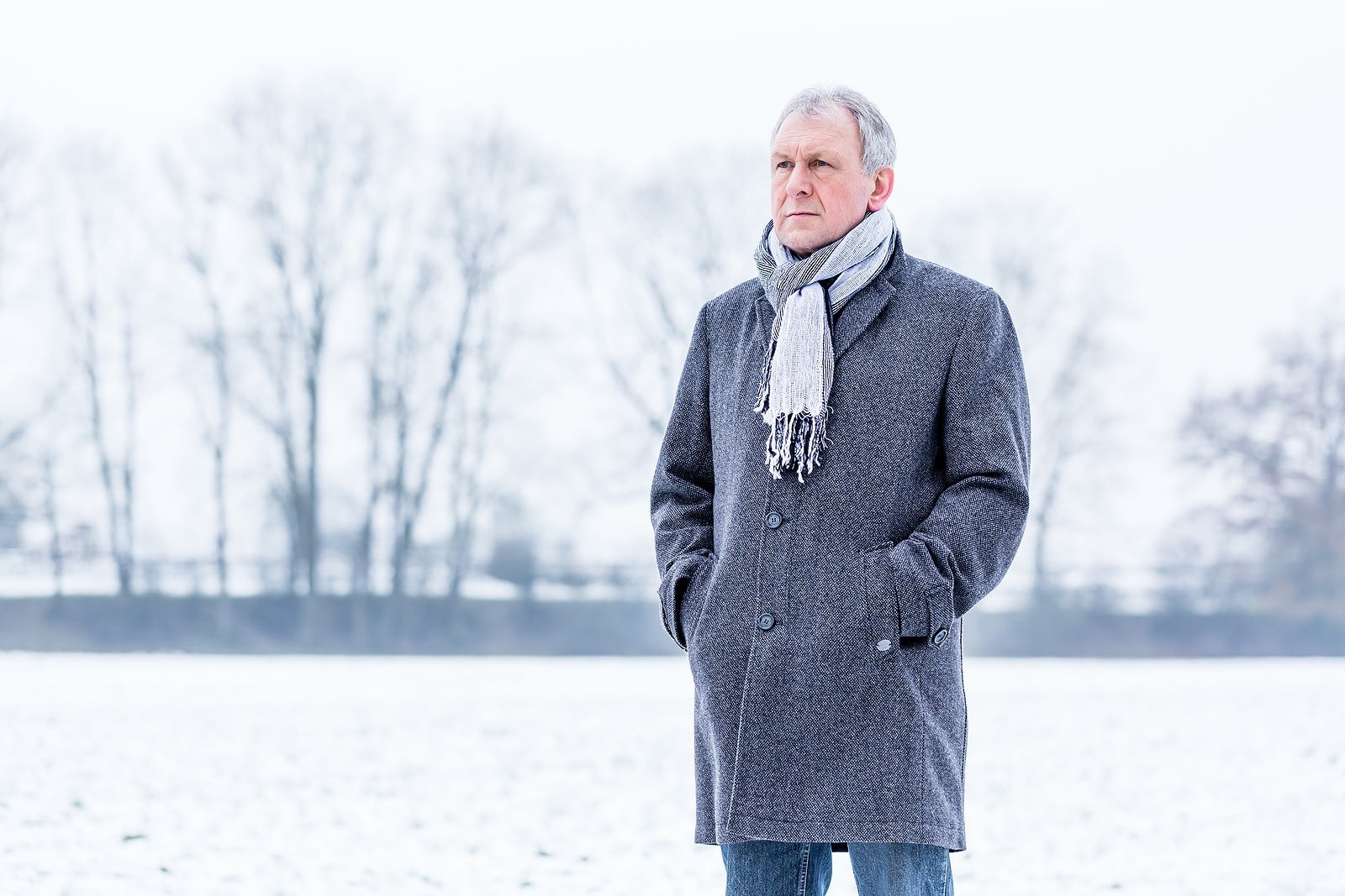 Older man in gray coat standing in winter