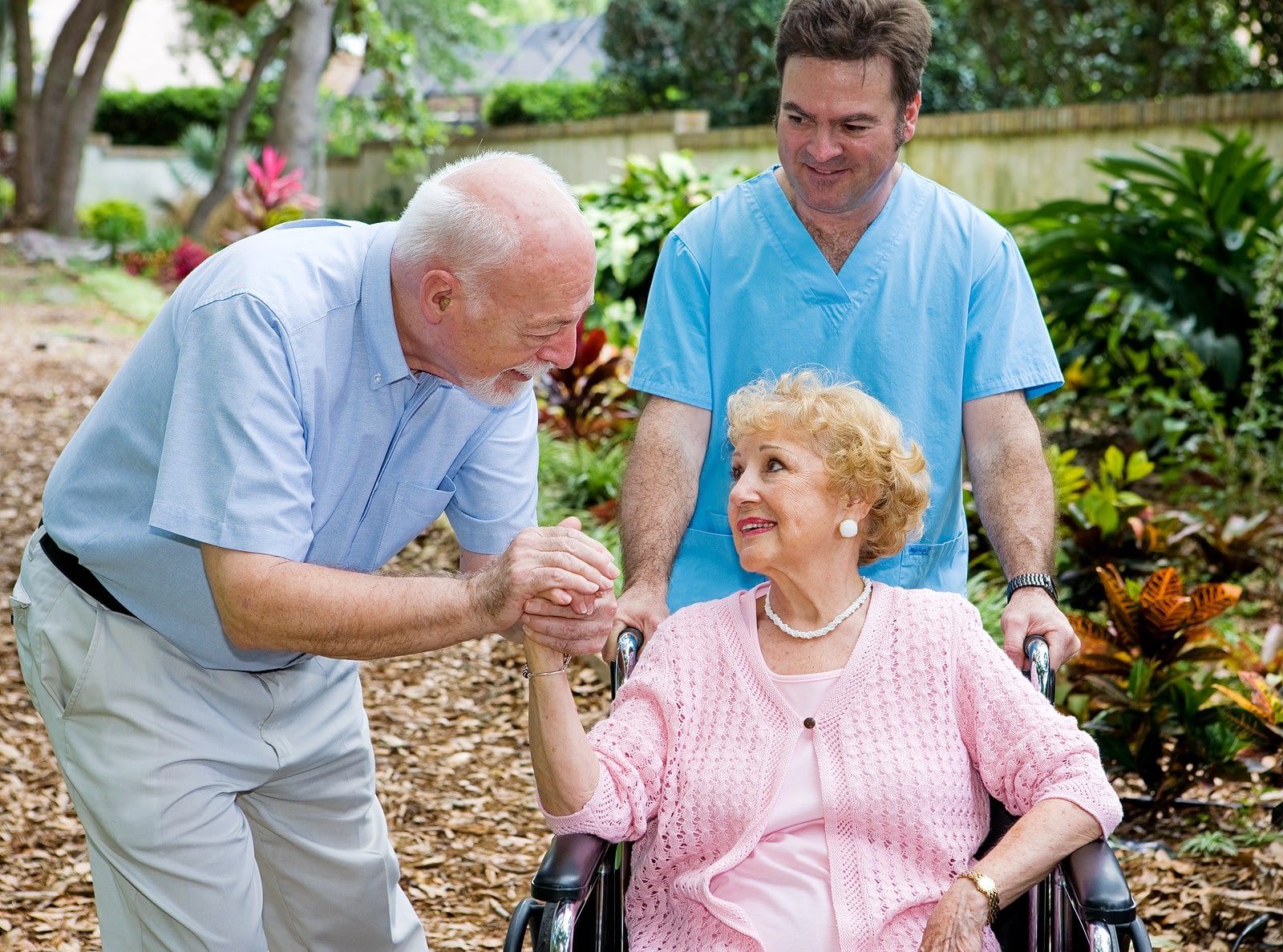 Elderly woman in wheelchair with caregiver and friend