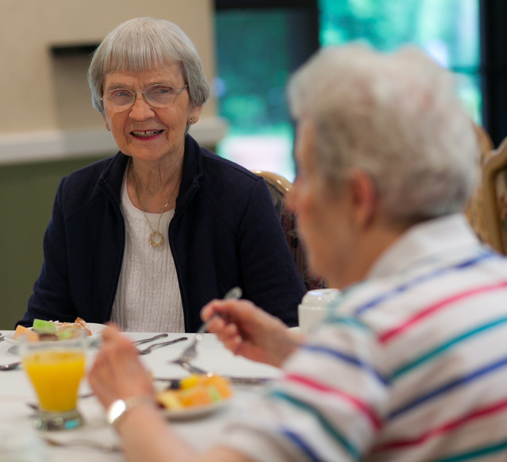 Two elderly women chatting over breakfast table