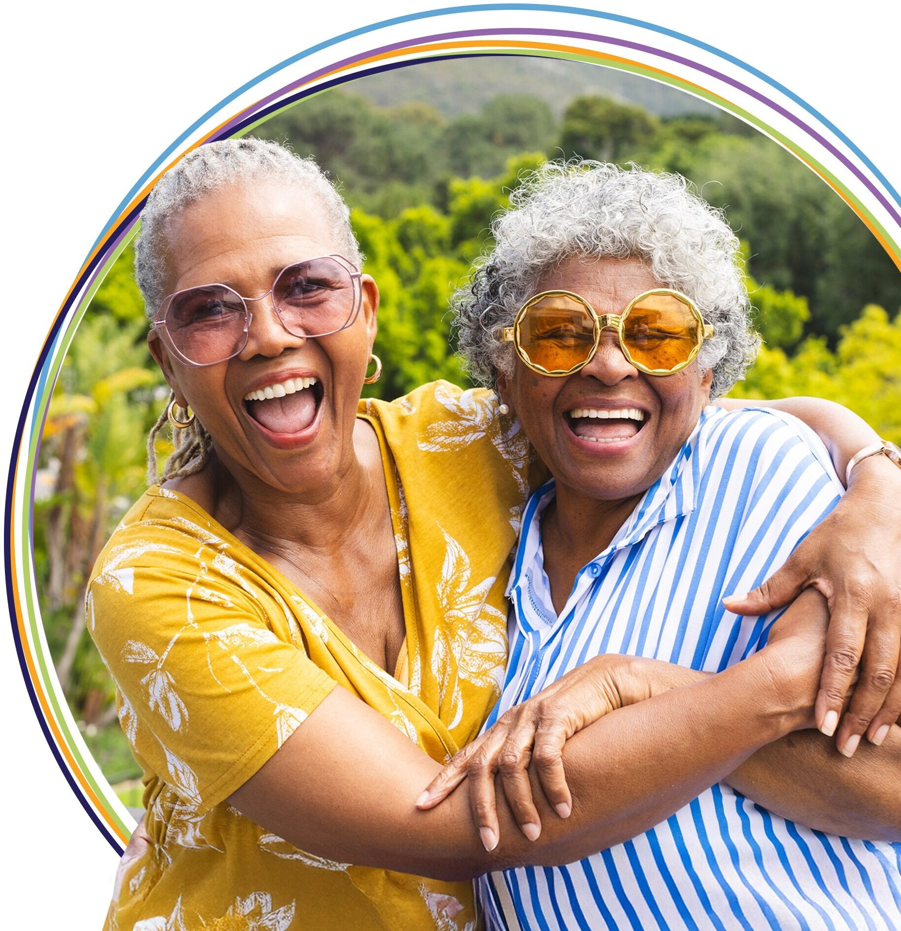 Two older women laughing and hugging outdoors