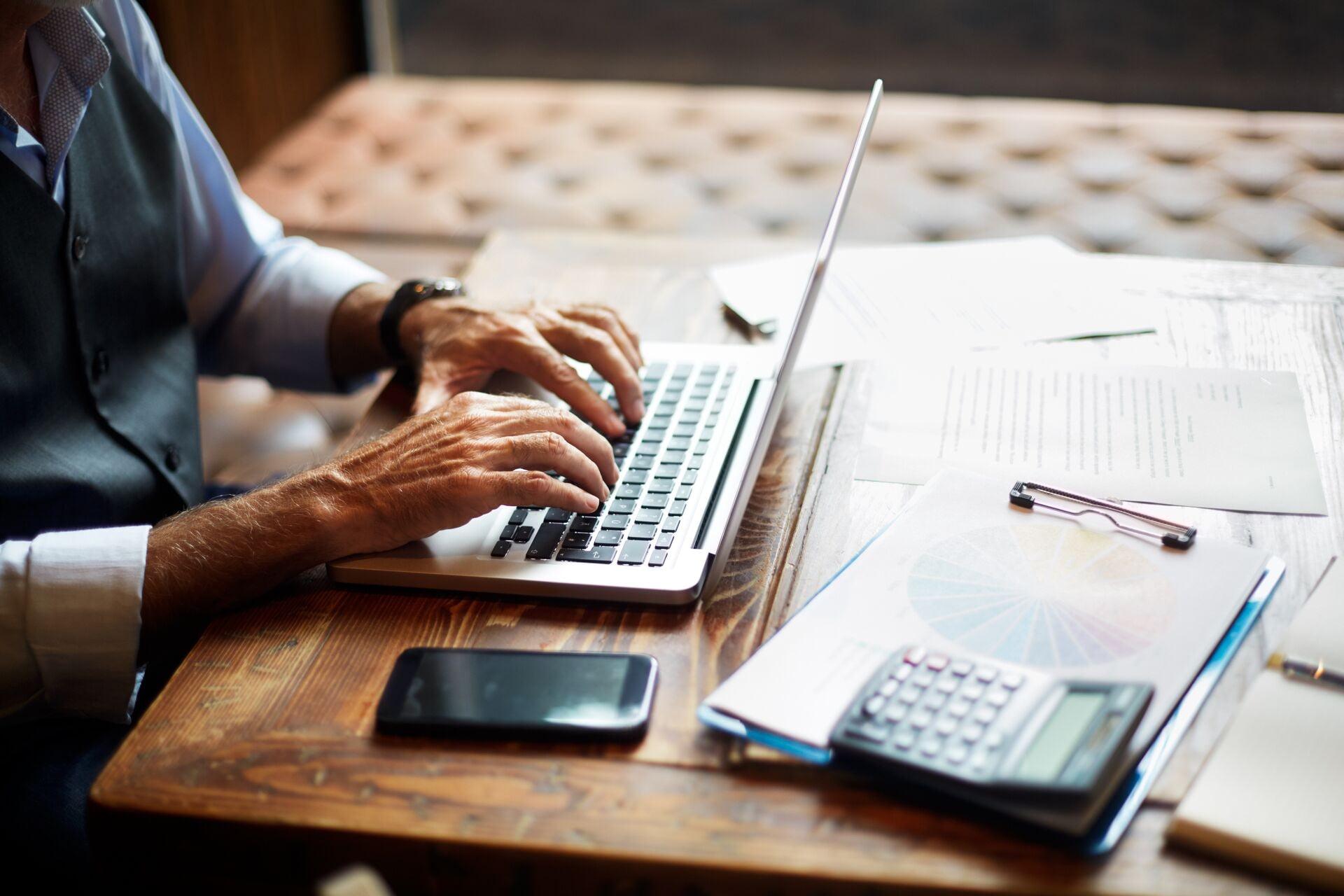 Man typing on laptop at wooden desk
