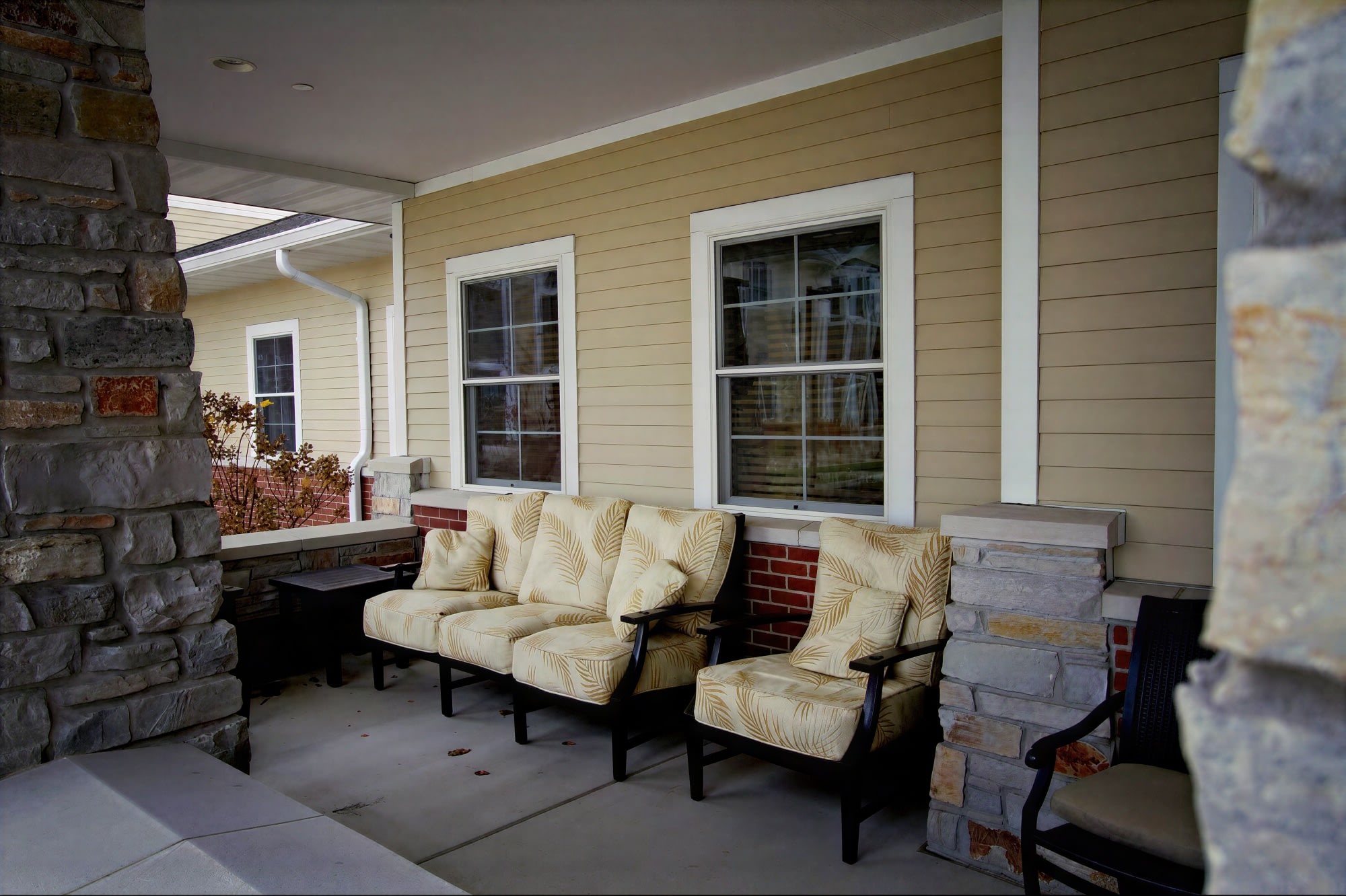 Cozy front porch with cushioned chairs and stone pillars