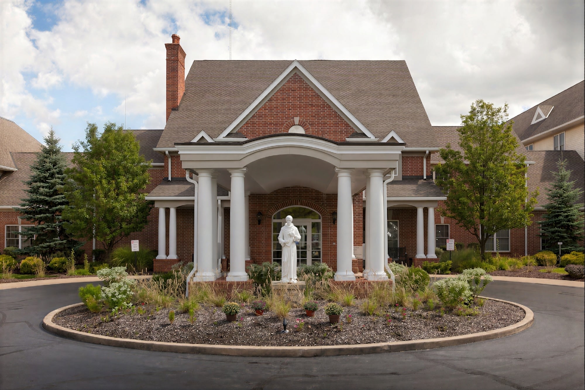Brick church entrance with white columns and statue