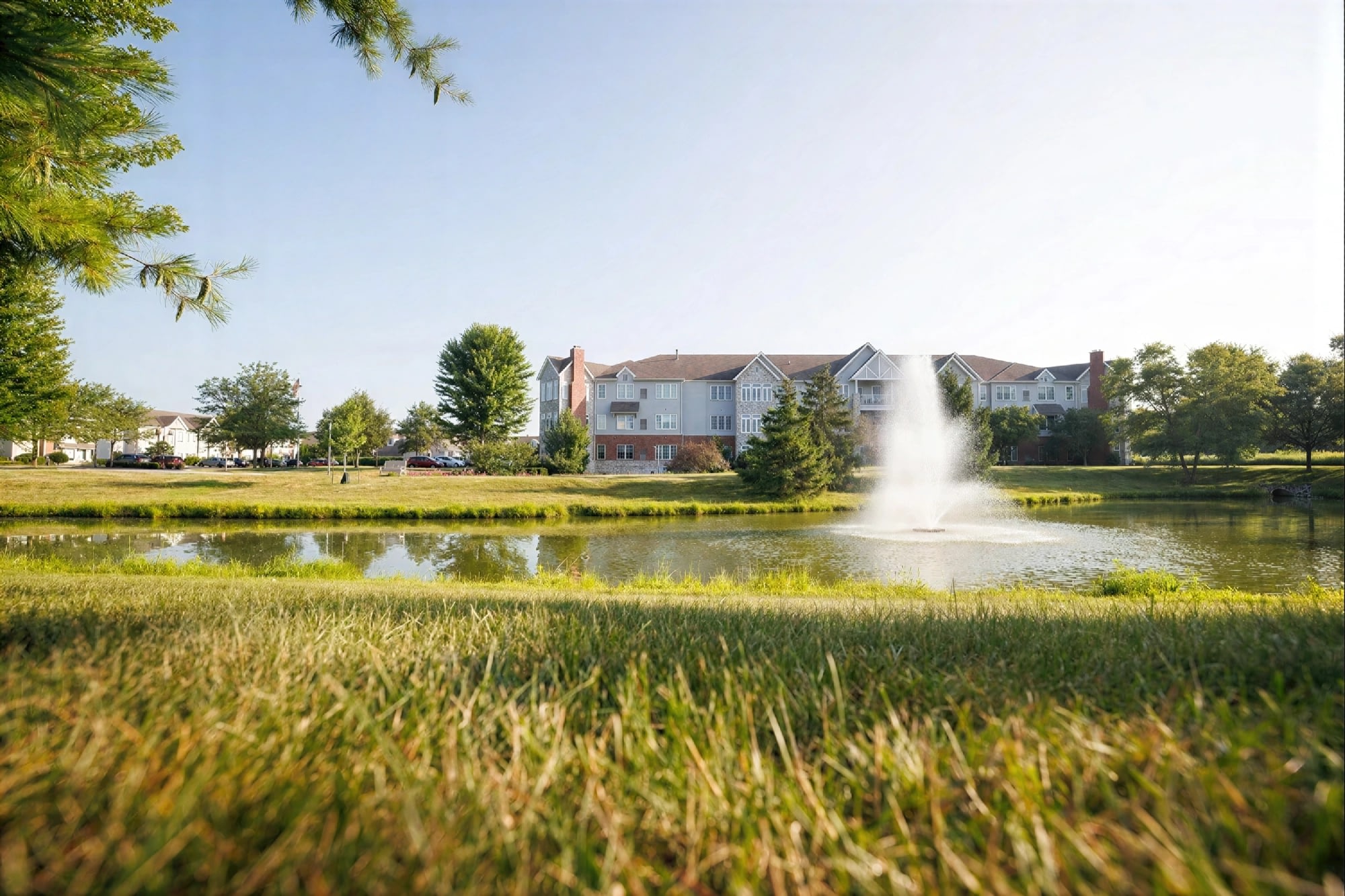 Apartment buildings behind pond with fountain and trees