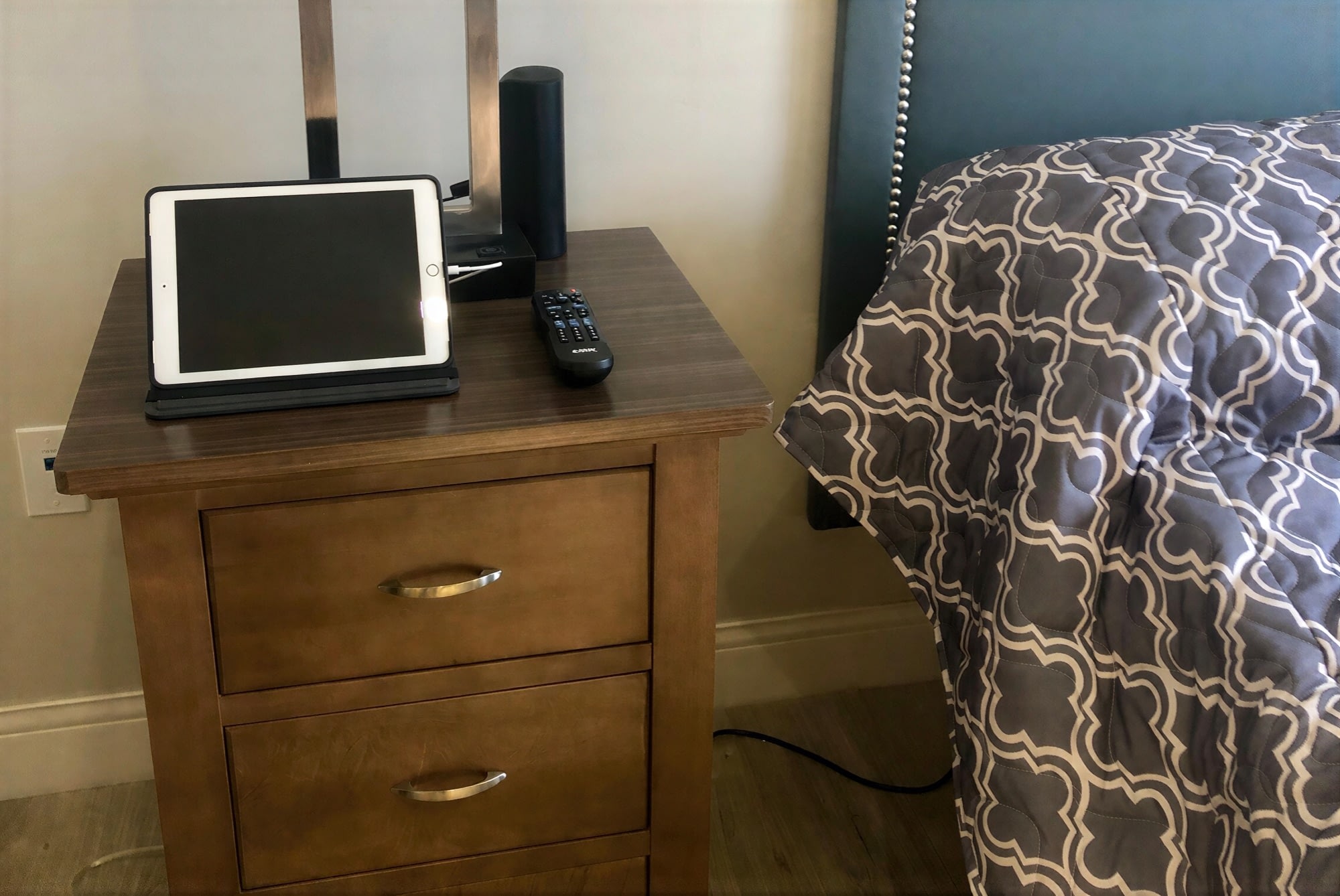 Tablet and remote on wooden bedside table
