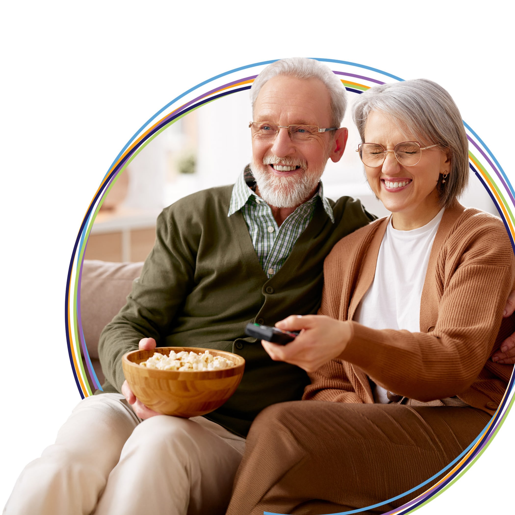 Smiling senior couple watching TV with popcorn