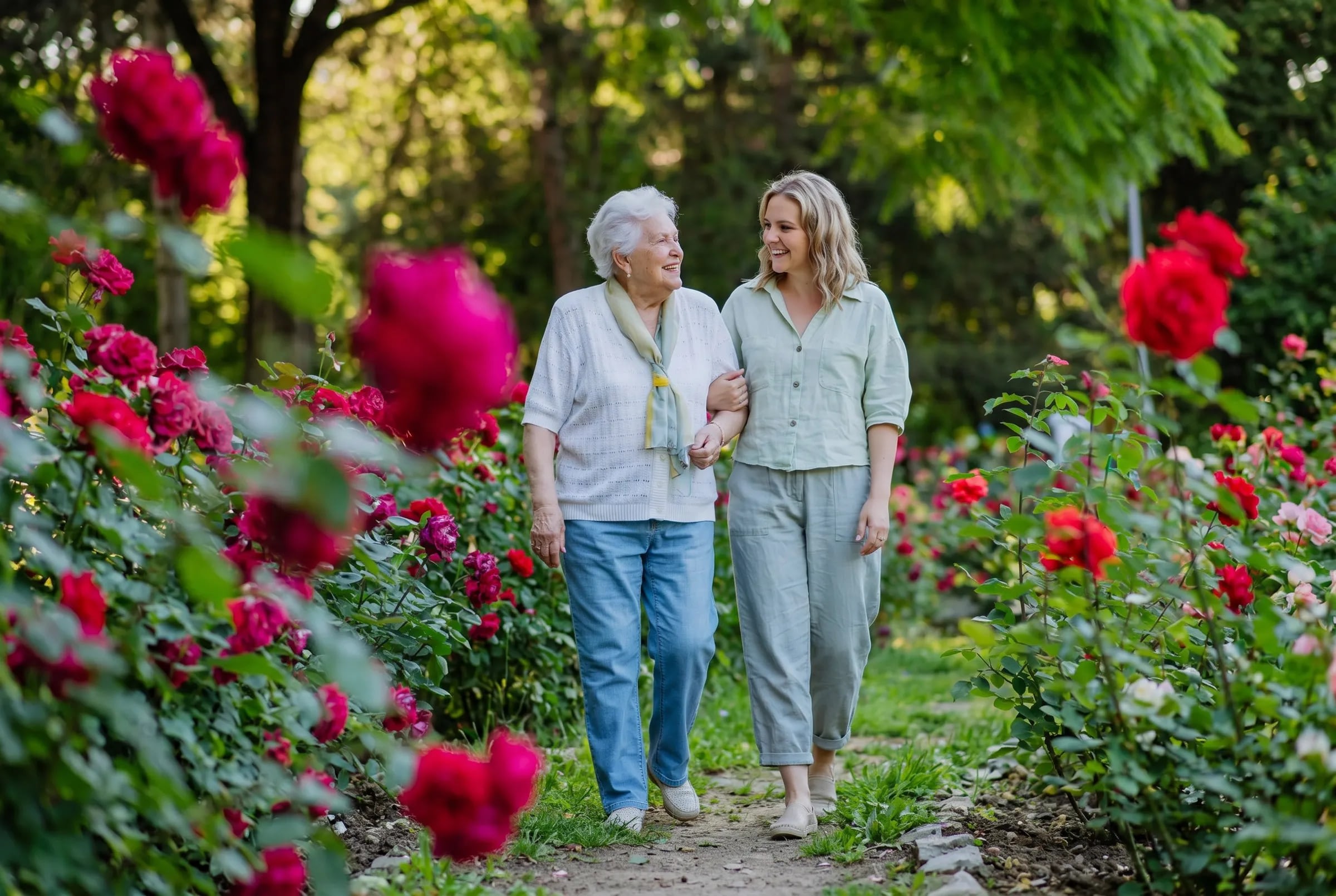 Senior women and caregiver walking through blooming rose garden