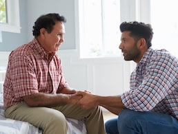 Two men holding hands in supportive conversation