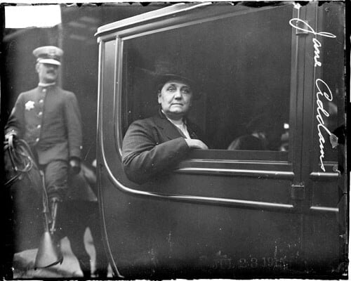Woman looking from carriage window, uniformed rider behind