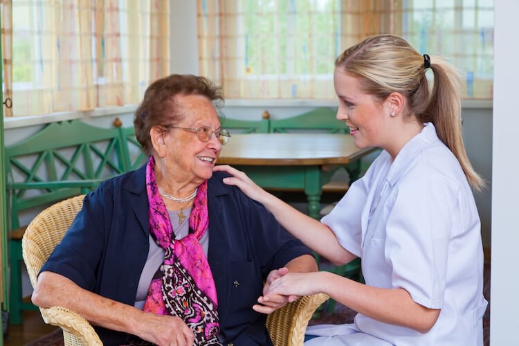 Caregiver comforting elderly woman in bright room