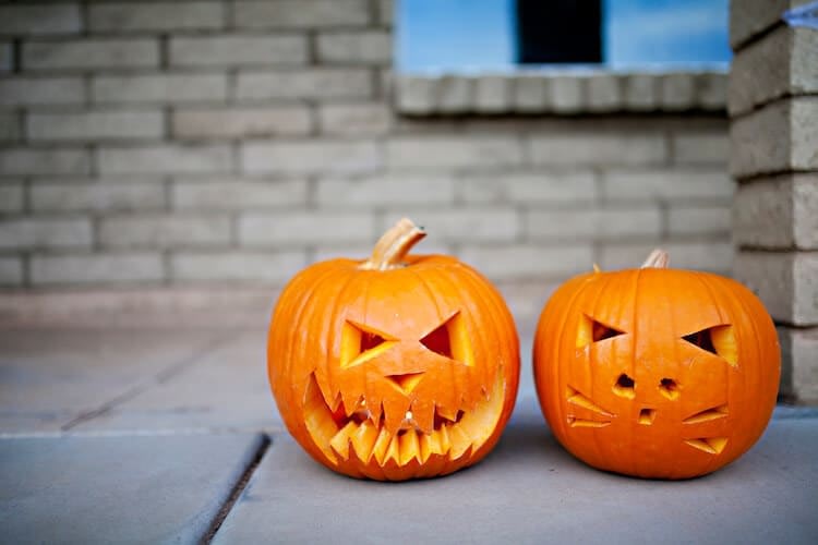 Two carved Halloween pumpkins on brick porch