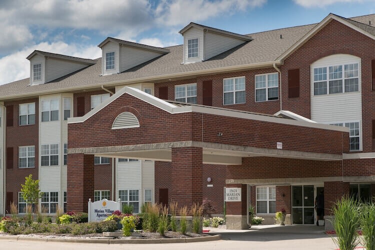 Brick apartment building with covered entrance and landscaping