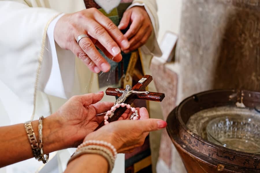 Priest blessing rosary with holy water