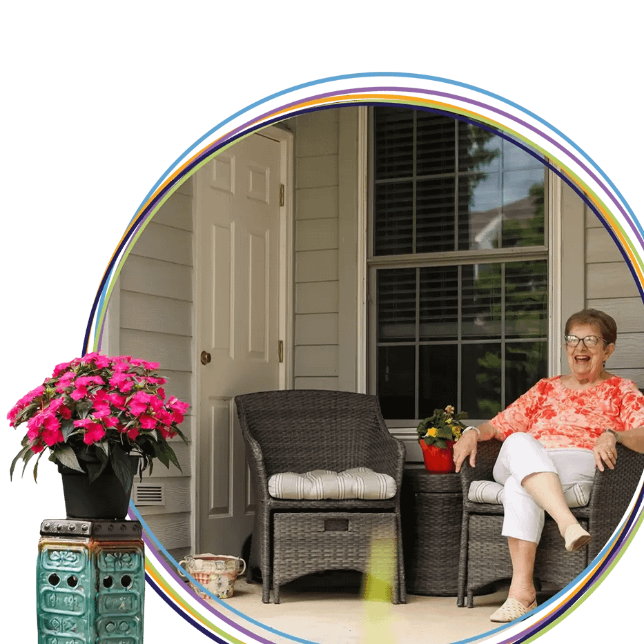 Smiling elderly woman sitting on porch with flowers