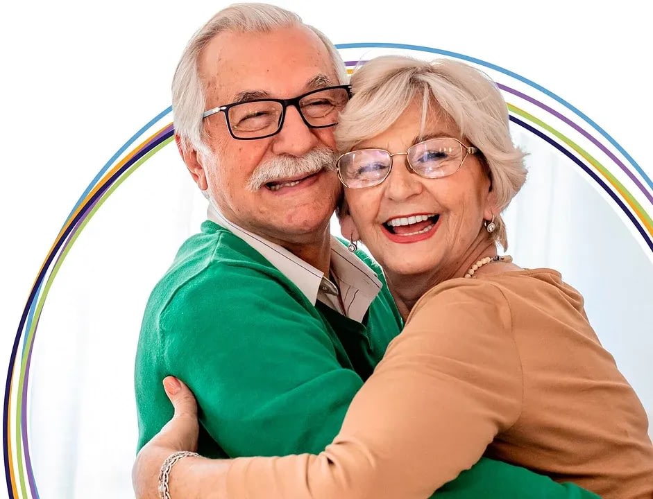 Smiling elderly couple hugging in front of rainbow
