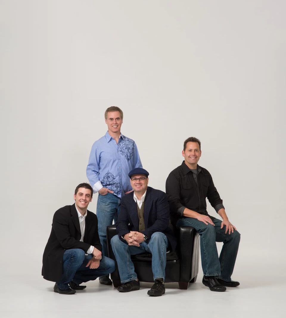 Four men posing in studio with neutral background