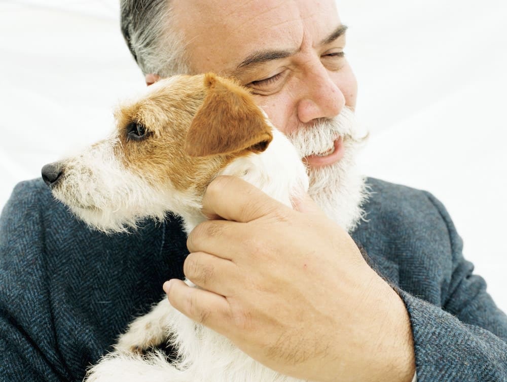 Older man smiling and hugging Jack Russell Terrier