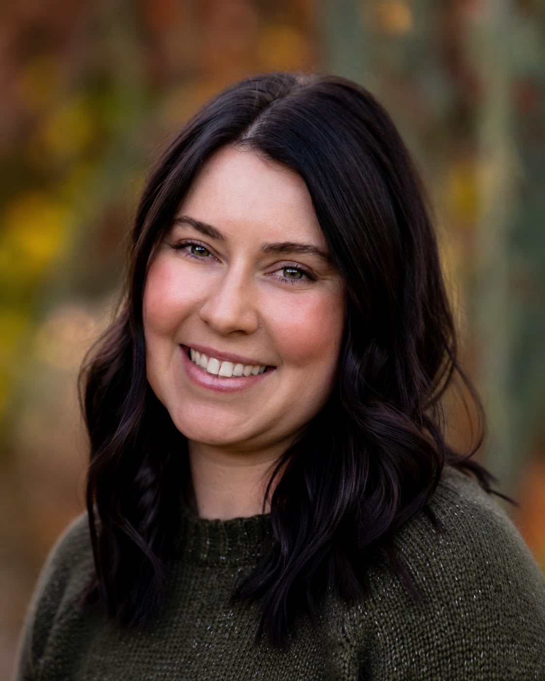 Smiling woman with dark hair outdoors in autumn