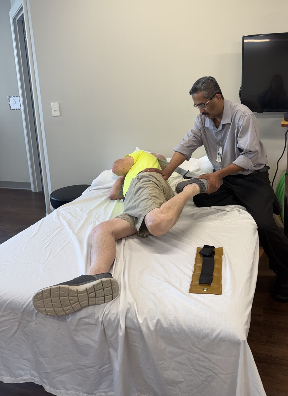 Therapist assists patient with leg exercise on treatment table