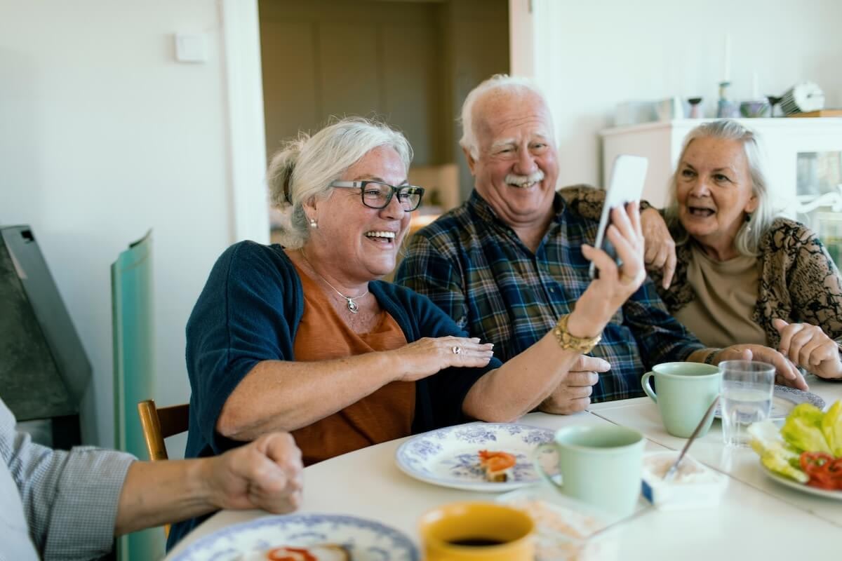 Three seniors laughing during smartphone video call