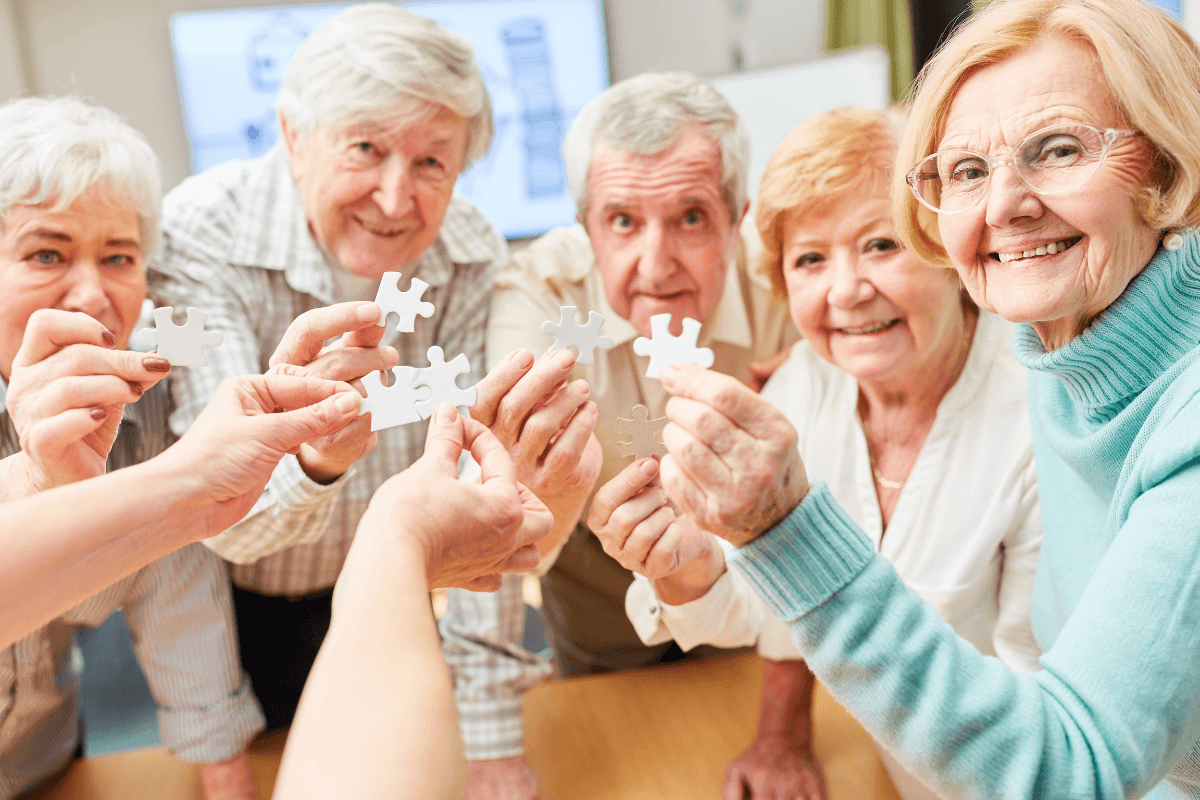 Happy seniors playing the puzzle as memory training in a community.