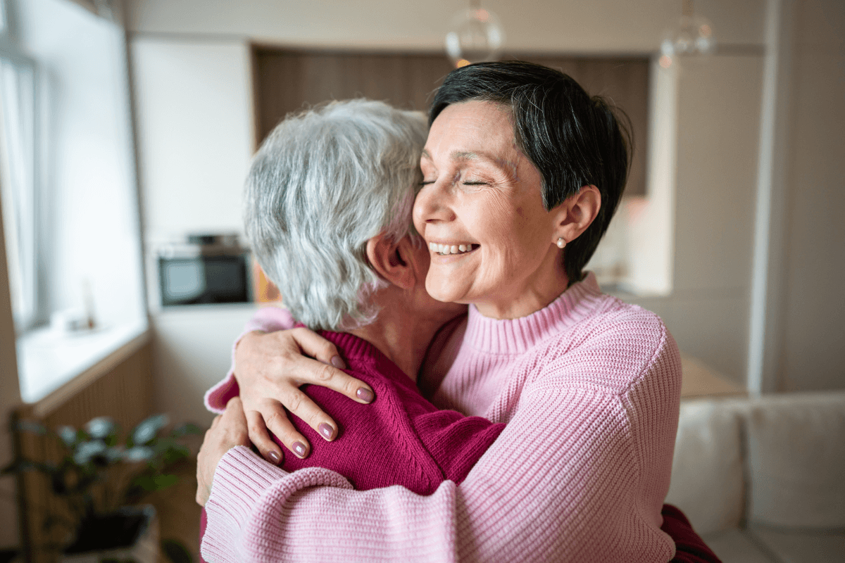 Two women warmly hugging in cozy home