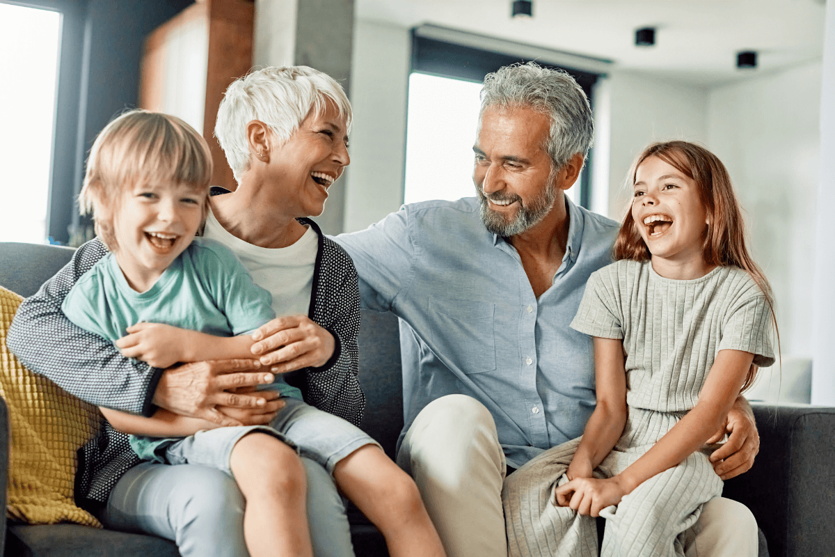 Grandparents laughing with two children on couch