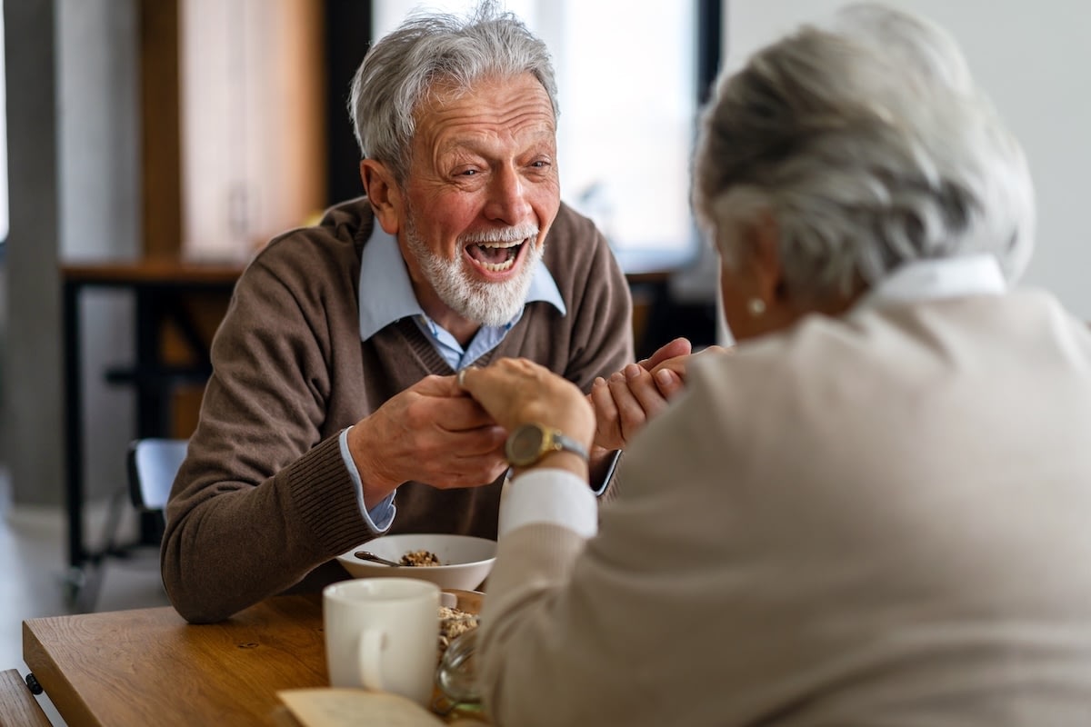 Elderly couple laughing over breakfast at table