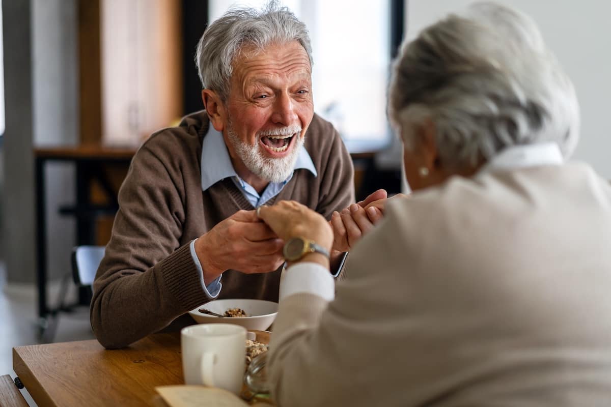 Elderly couple laughing over breakfast at table