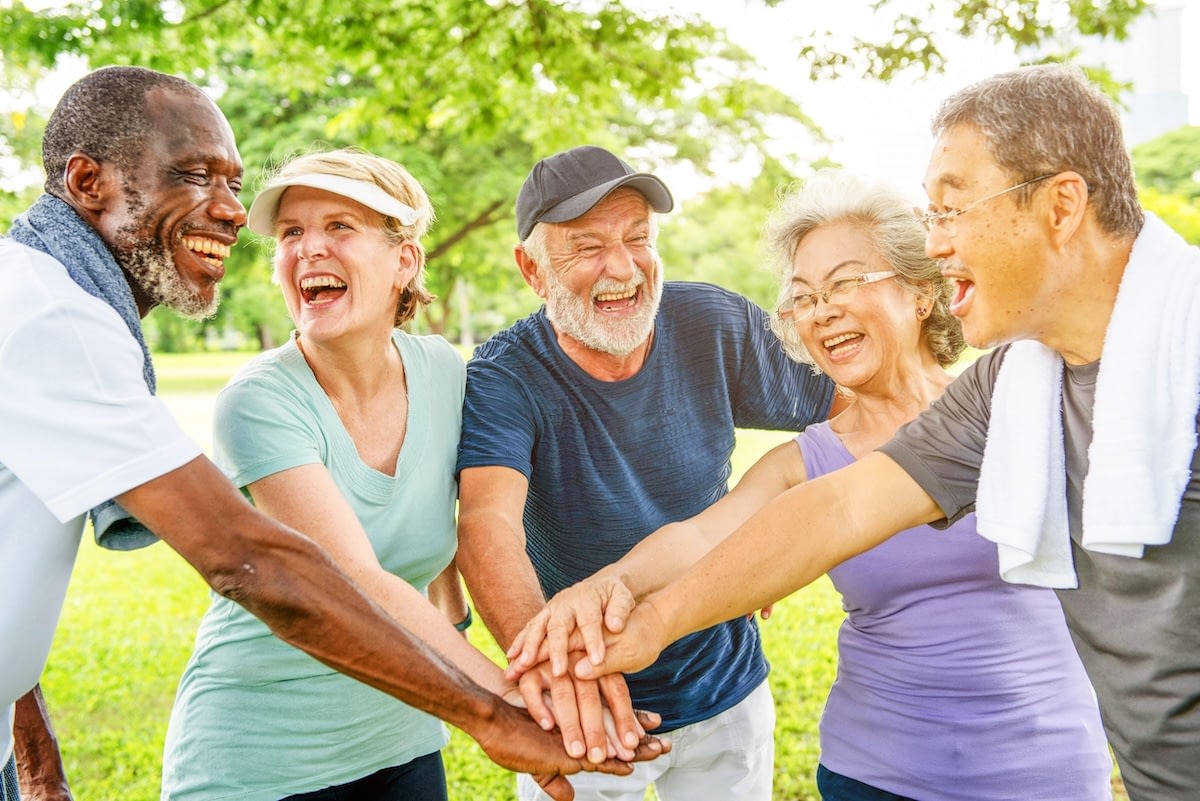 Group of seniors stacking hands in park