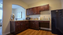 Compact kitchenette with dark wood cabinets and refrigerator