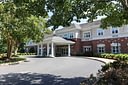 Brick building with white-columned entrance and driveway